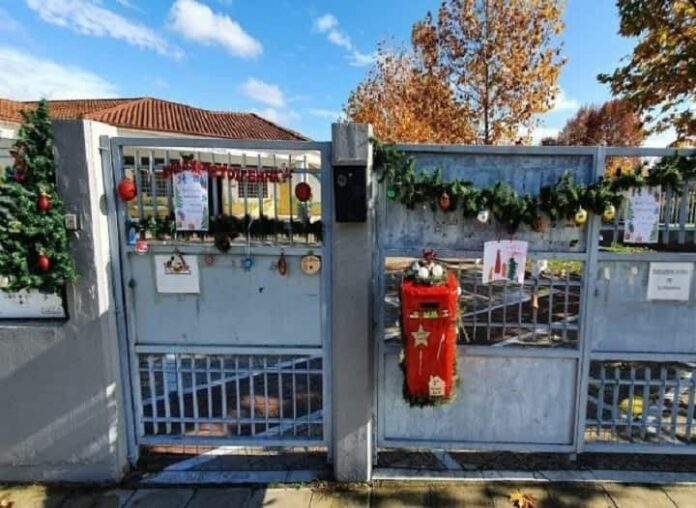 Παιδιά και γονείς κρεμούν στολίδια στην κλειστή πόρτα του 3ου Νηπιαγωγείου Λάρισας